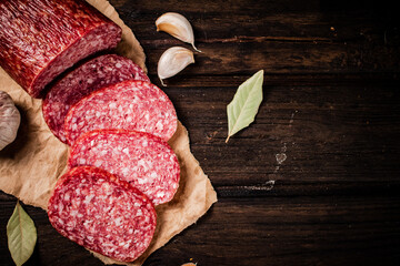 Sticker - Pieces of salami sausage with garlic and bay leaf on paper. 