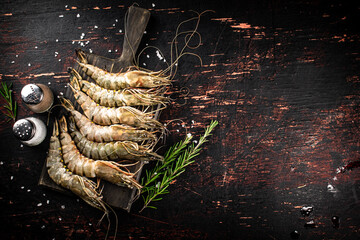 Canvas Print - Raw shrimp on a cutting board with spices and rosemary.