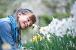 Happy child girl playing in summer garden enjoying sweet scent of white narcissus flowers on sunny day
