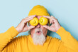 © ADDICTIVE STOCK - Amazed senior man covering eyes with lemons