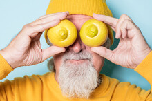 Senior Man Covering Eyes With Lemons