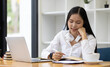 © Wasan - Businesswoman in office working with laptop and writing work schedule.