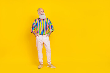 Poster - Photo of satisfied retired man with white beard dressed striped shirt white trousers look empty space isolated on yellow color background