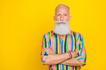 Poster - Photo of handsome serious retired man with white beard dressed striped shirt standing arms crossed isolated on yellow color background