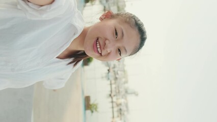 Poster - VERTICAL VIDEO: Young woman making video call with mobile phone on seascape background