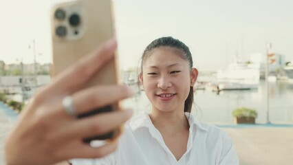 Poster - Young woman making video call with mobile phone on seascape background