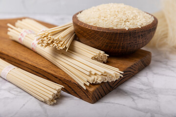 Rice noodles.Rice and noodles with rice flour in a wooden plate on a white marble background.Close-up.Useful and healthy food. Place for text. Copy space.