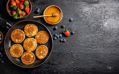 Poster - Pancakes in a frying pan with fresh berries and honey. 