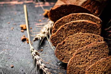 Poster - Slices of fresh bread on the table with spikelets. 