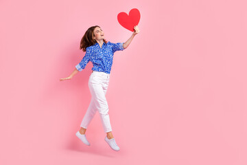 Sticker - Full length photo of pretty impressed lady wear print shirt jumping holding heart empty space isolated pink color background