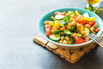 Wall Mural - Chickpea salad with tomatoes, cucumber, parsley, onions in a plate, selective focus. Healthy vegetarian food, oriental and Mediterranean cuisine. Chick peas salad