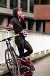 © Jorge Elizaquibel - Portrait of bike courier woman leaning on a banister and talking by walkie-talkie.