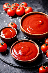 Canvas Print - Tomato sauce in a wooden plate on a stone board with salt. 