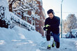 © Drazen - Male athlete using smart watch while jogging on snowy street.