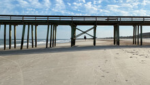Person Sitting Under The Pier On The Beach