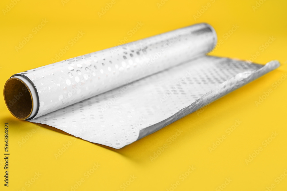 Roll of aluminium foil on yellow background