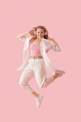 Wall Mural - Young woman in headphones dancing on pink background