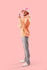 Wall Mural - Young man in bucket hat with disposable electronic cigarette on pink background