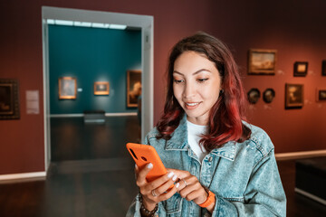 Girl uses the application on her smartphone as an audio guide and a virtual tour of the Museum of Fine Arts and an exhibition of paintings.