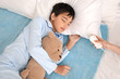 © Pixel-Shot - Little boy with toy and mother turning on electric heating pad in bedroom