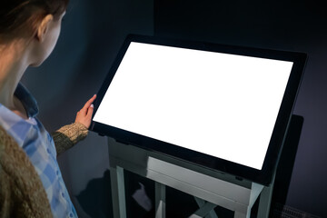 White screen, mock up, future, copyspace, template, technology concept. Woman looking at blank interactive touchscreen white display of electronic kiosk at futuristic exhibition or museum