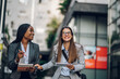© Zamrznuti tonovi - Two multiracial business woman meeting outside and using a tablet