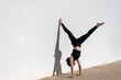 © Rob Wilkinson - Woman doing a handstand against a white wall in the sun