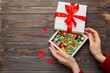 © sosiukin - Female hands with delicious candies in box on color background