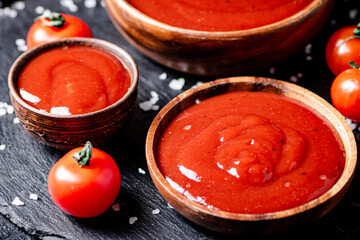 Sticker - Tomato sauce in a wooden plate on a stone board with salt. 