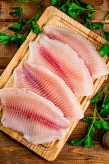 Sticker - Raw fish fillet with parsley on a cutting board. 