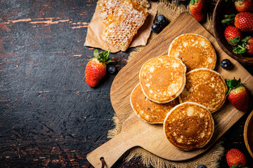 Poster - Pancakes on a wooden cutting board with honey and berries.