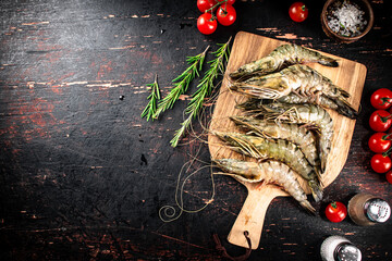 Canvas Print - Raw shrimp on a wooden cutting board with tomatoes and spices. 