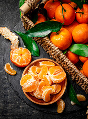 Wall Mural - Ripe tangerines with leaves in a basket. 