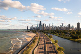 Fototapeta Tęcza - Downtown Chicago city skyline aerial centered over traffic along Lake Shore Drive between South Lagoon and Lake Michigan on a sunny day with fluffy white clouds in a blue sky above.