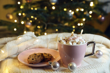 Wall Mural - Cup of tasty cocoa with marshmallows and cookies on knitted plaid near Christmas tree indoors