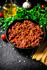 Wall Mural - Bolognese sauce in a frying pan with pasta dry and parsley. 