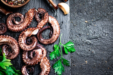 Sticker - Pieces of fresh octopus on a stone board with greenery. 