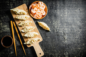 Canvas Print - Dumplings gyoza with shrimp on a wooden cutting board with soy sauce. 