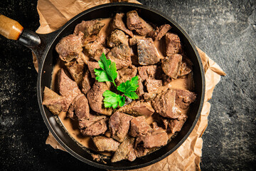 Canvas Print - Liver in a frying pan on paper with a sprig of parsley. 