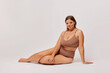 © South House Studio - Plus size self enjoyed woman wearing lingerie sitting on a floor isolated over white background. Body Positive concept