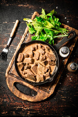 Poster - Liver in a frying pan on a cutting board with parsley and spices. 