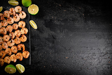 Wall Mural - Grilled shrimp on a stone board with pieces of lime. 