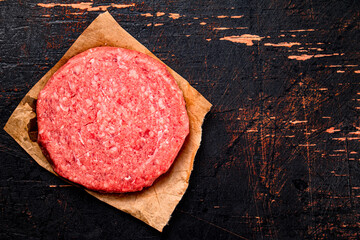 Poster - Raw burger on paper. On a rustic dark background.