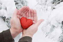 Man Hands Holding A Carved Wooden Heart For Valentine's Day In The Snow