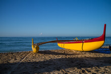 Yellow And Red Hawaiian Outrigger Canoe On The Beach In Hawaii.