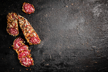 Poster - Sliced salami sausage. On a black background.