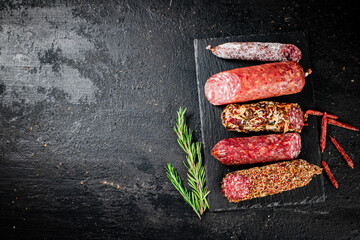 Poster - An assortment of delicious salami sausage on a stone board with rosemary. 