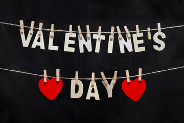 Clothes pegs pin and valentine's day text red wooden hearts on rope on white black background Valentines day concept.