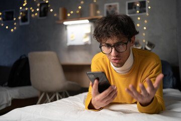 Upset angry male feel outraged by bad wrong work of smartphone app. Telephone problem. Worried nervous young man get too much spam messages.