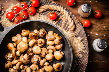 Sticker - Frying pan with fried mushrooms on a wooden tray. 